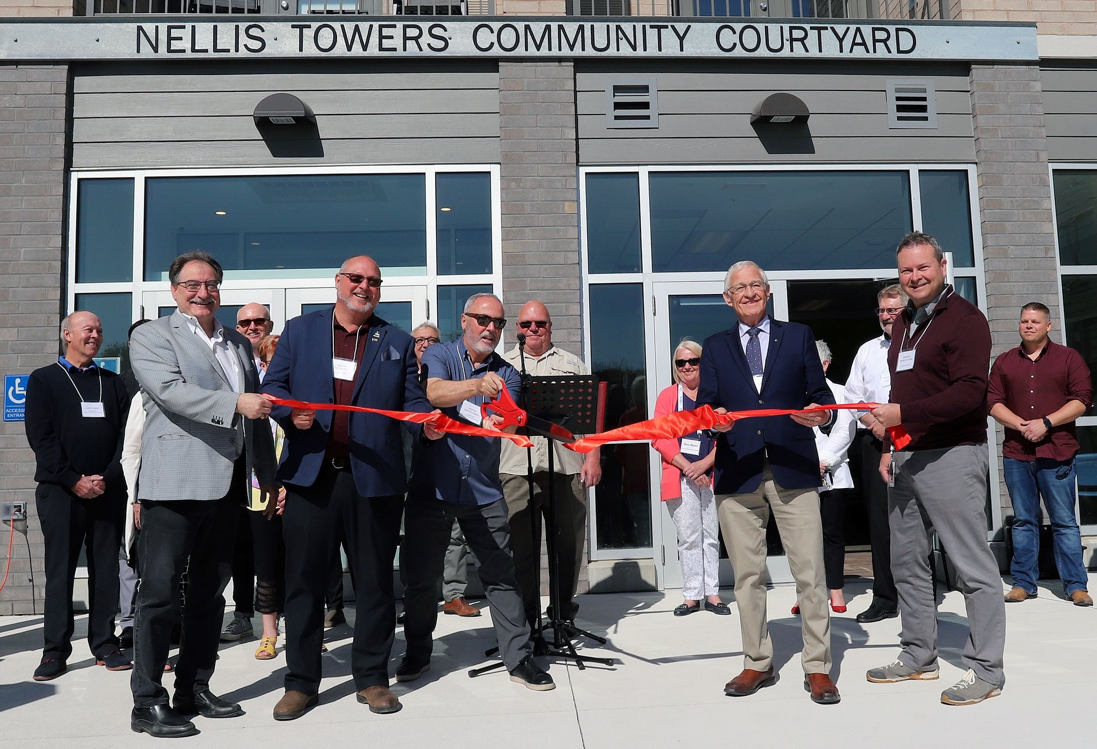 Local dignitaries cutting the ribbon on the brand new Nellis Towers affordable housing building