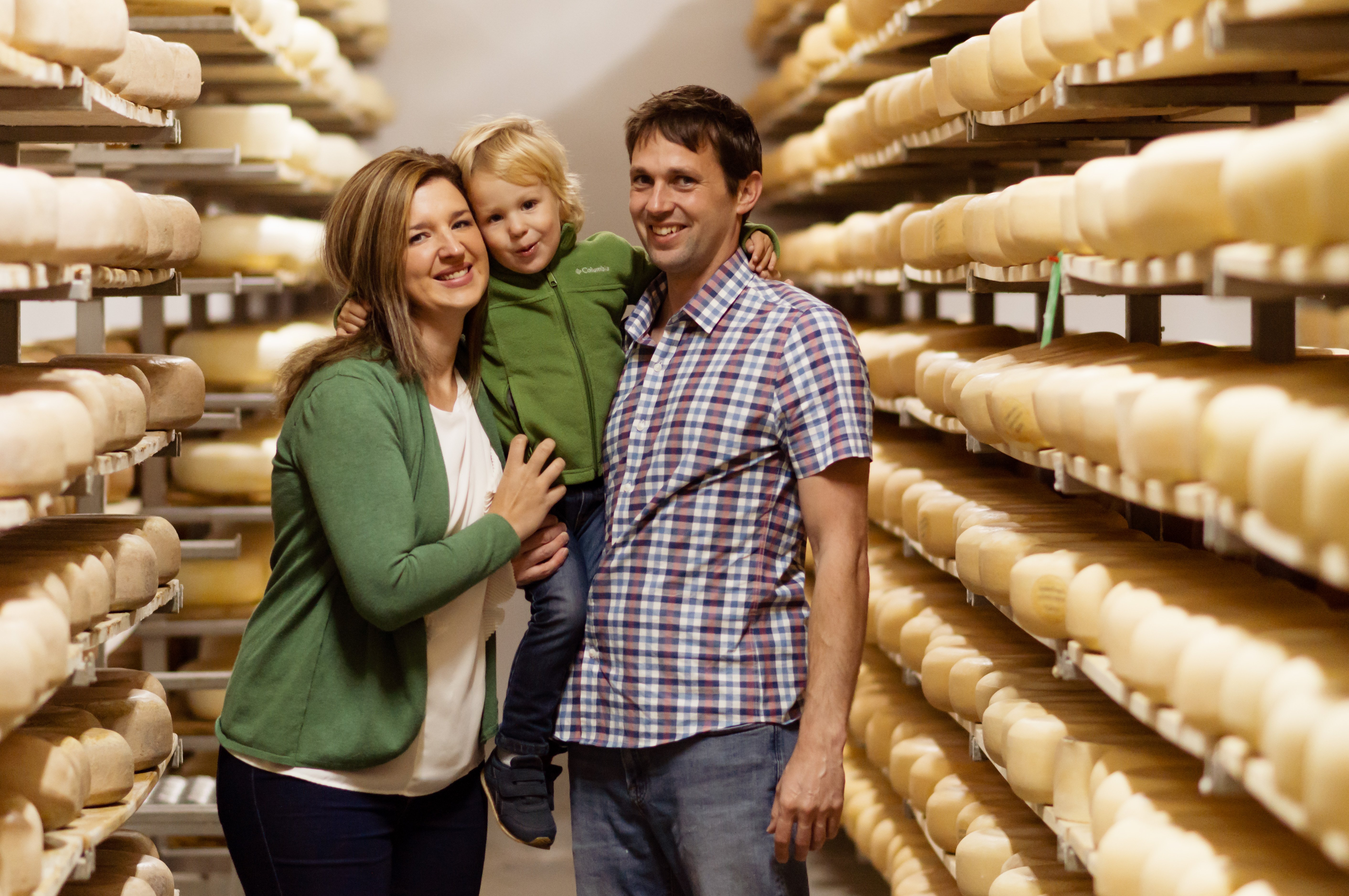 Gunn's Hill Artisan Cheese owners standing in between a row of cheese