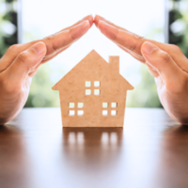 A house cutout with two hands overtop of it